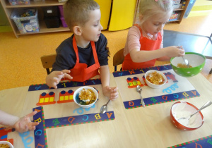 Dzieci nakładają płatki miodowe łyżką do miski.